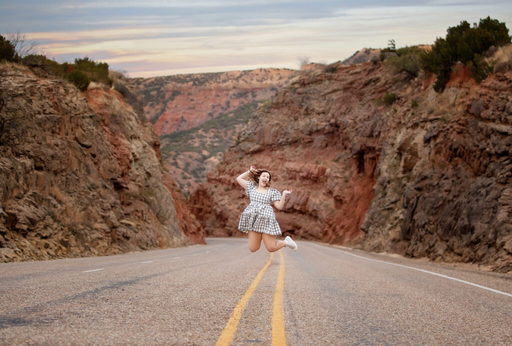 Senior jumping in the middle of the road in the Claude crossing canyons