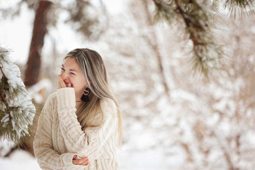 Senior girl standing in the snow laughing and looking happy 