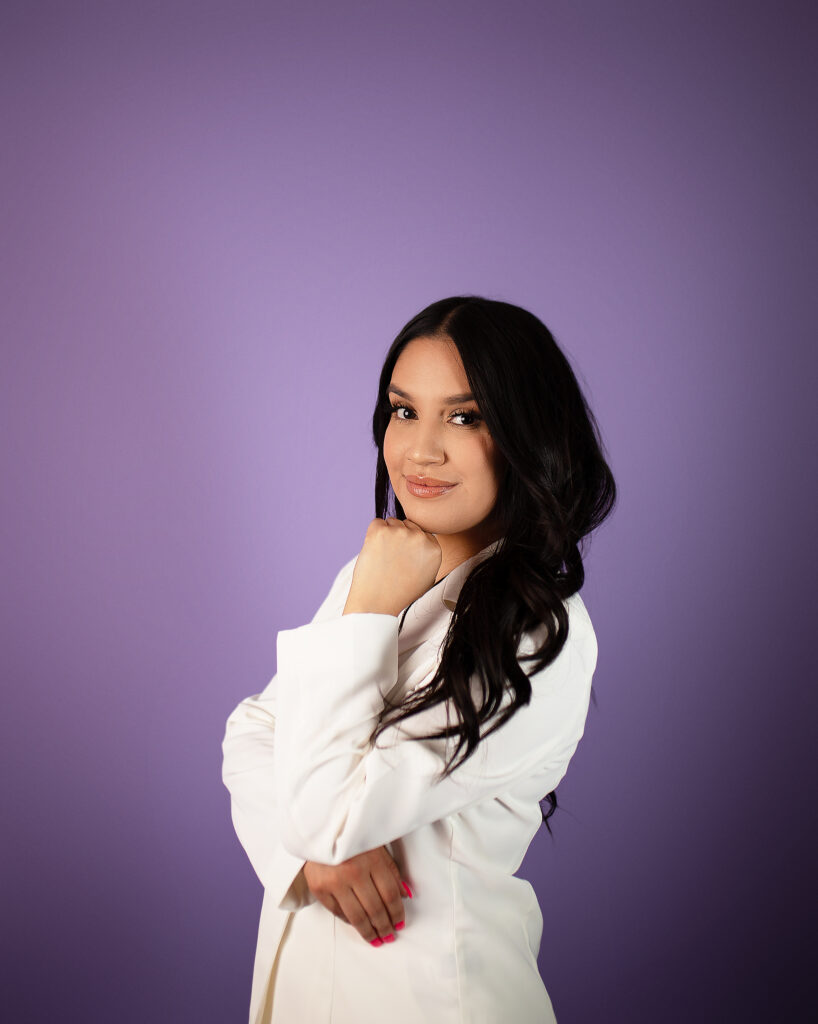 College grad studio session, white outfit against a purple background