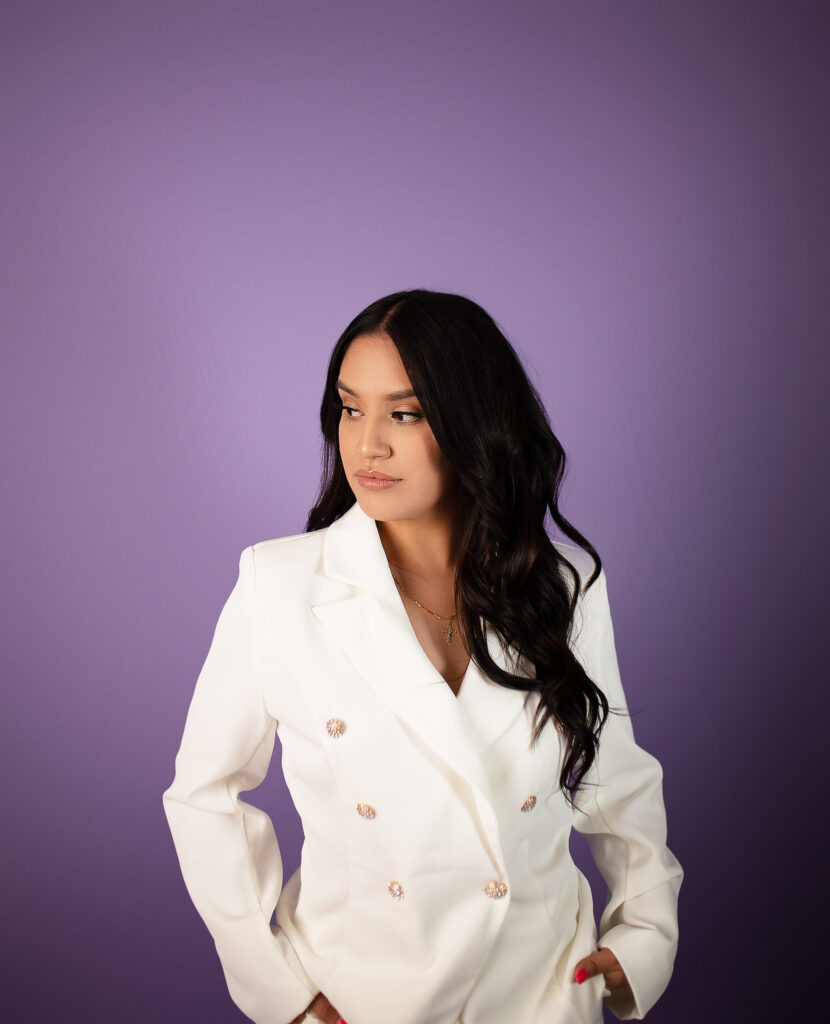 Girl looking to the side in a white outfit against a purple savage seamless background