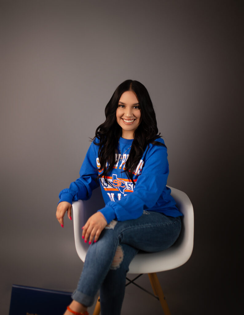girl sitting in white chair with a South Plains College grad sweatshirt on