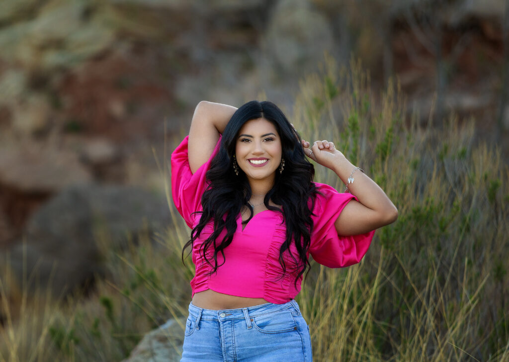 High school senior posing in a pink shirt at her senior session 