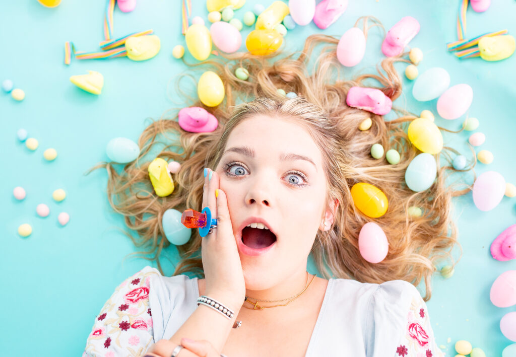 blue eyed, blonde haired Tulia High School senior laying on the ground surrounded by Easter Candy 