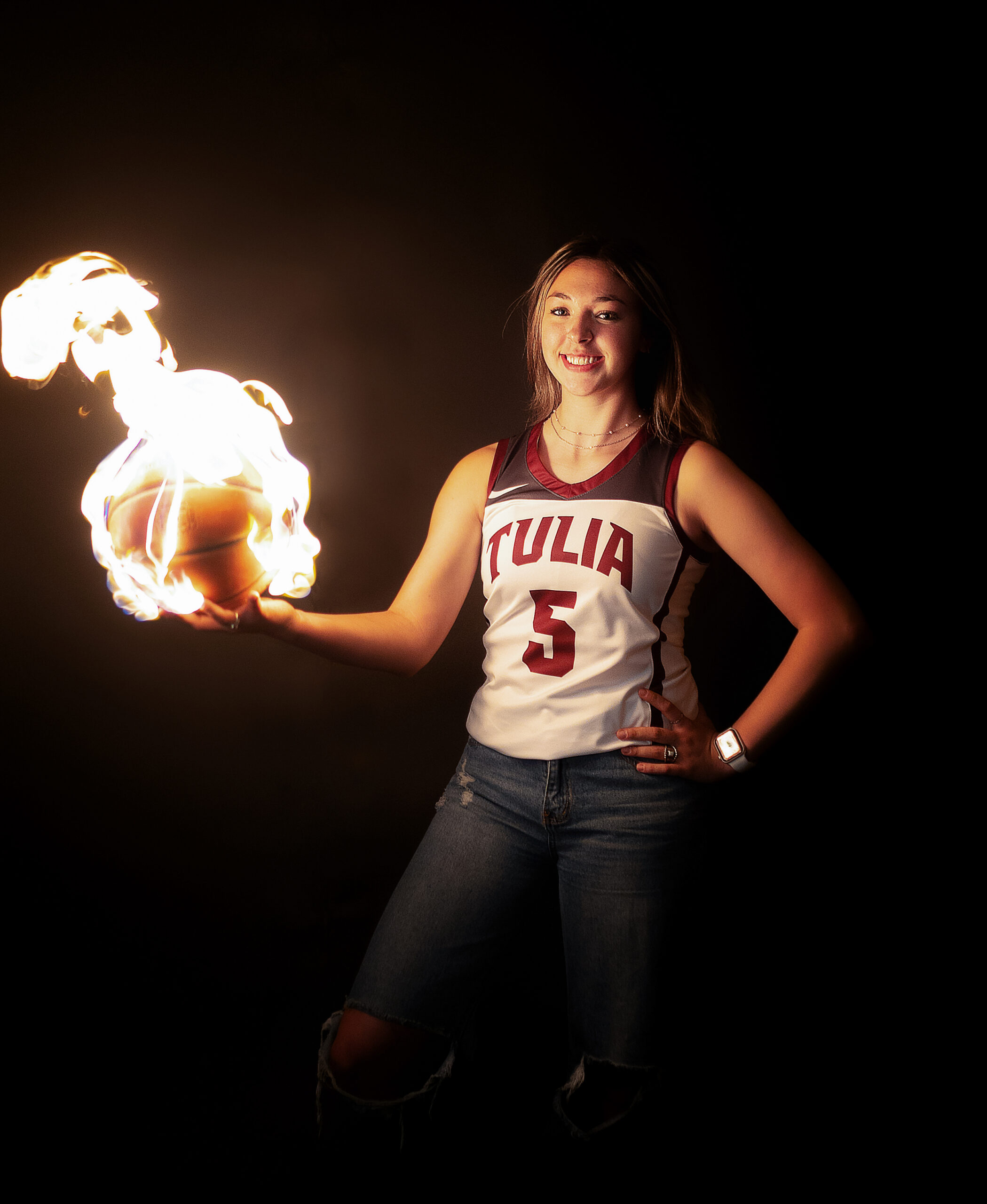Senior high school girl holding a basketball on fire during her studio senior session