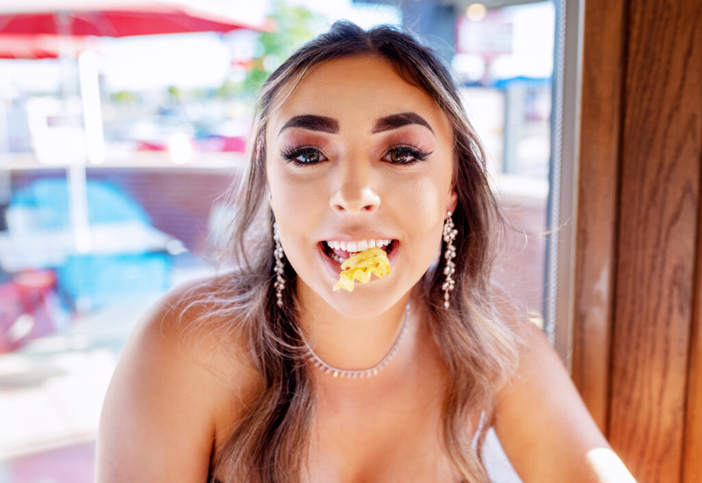 Tulia High School senior holding a Chick-Fil-A waddle fry in her mouth while wearing a prom dress at the Amarillo restaurant 